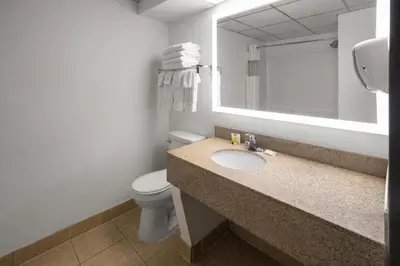 a bathroom with a sink and a toilet and a mirror at Baymont by Wyndham Westampton in Westampton Township