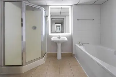 a bathroom with a shower and a sink and a tub at Baymont by Wyndham Westampton in Westampton Township
