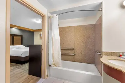 a bathroom with a shower and a sink and a bed at Econo Lodge Woodbridge in Iselin