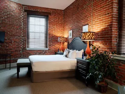 a bedroom with a bed and a brick wall at Lancaster Arts Hotel in Lancaster
