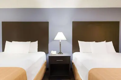 a hotel room with two beds and a lamp at Days Inn by Wyndham Wilkes Barre in Wilkes-Barre