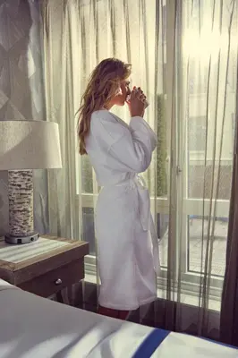 a woman in a white dress looking out of a window at Artezen Hotel in New York