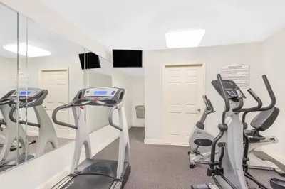 a gym with treadmills and ellipticals in front of a mirror at Days Inn by Wyndham Springfield/Phil.Intl Airport in Springfield