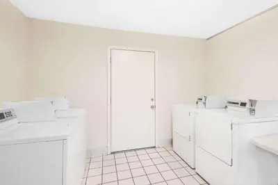 a white laundry room with white appliances and a door at Days Inn by Wyndham Springfield/Phil.Intl Airport in Springfield