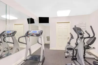 a gym with three treadmills and a mirror at Days Inn by Wyndham Springfield/Phil.Intl Airport in Springfield