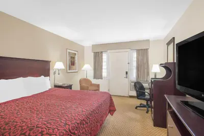 a hotel room with a red bed and a flat screen tv at Days Inn by Wyndham Springfield/Phil.Intl Airport in Springfield