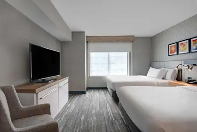 a hotel room with two beds and a flat screen tv at Hilton Garden Inn Hamilton in Bordentown