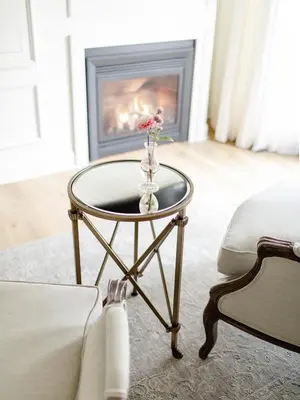 a glass table with a vase of flowers on it with a fireplace at Fairville Inn in Chadds Ford