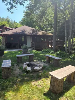 two picnic tables and a fire pit in a yard at Magnolia Streamside Resort in Canadensis