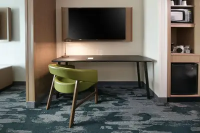 a hotel room with a desk and a green chair at Fairfield Inn & Suites by Marriott Pottstown Limerick in Pottstown