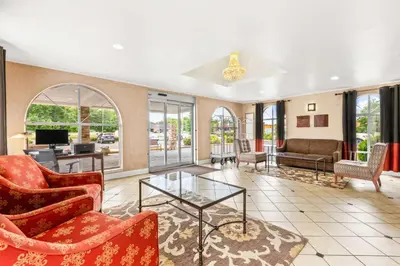 a living room with red chairs and a glass table at Best Western Hazlet Inn in Hazlet