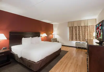 a hotel room with a bed and a flat screen tv at Red Roof Inn & Suites Mt Holly - McGuire AFB in Westampton Township