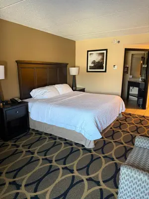 a hotel room with a bed and a chair at Hampton Inn Harrisburg/Grantville/Hershey in Grantville
