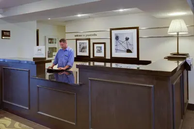 a man standing at a counter in a waiting room at Hampton Inn Harrisburg/Grantville/Hershey in Grantville