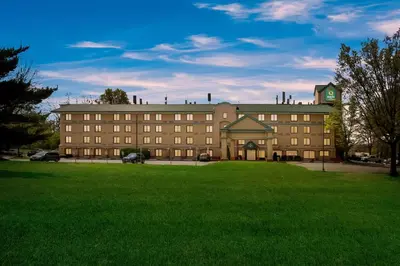 a large building with a green lawn in front of it at Quality Inn Near Princeton in Lawrence