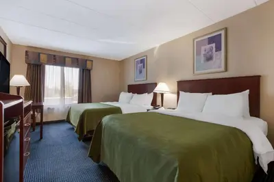 a hotel room with two beds and a piano at Quality Inn Near Princeton in Lawrence