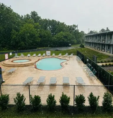 a swimming pool with lounge chairs and a building at Town Inn in Bordentown