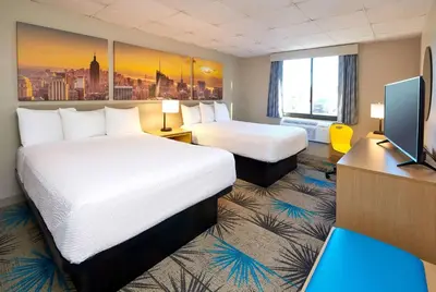 a hotel room with two beds and a flat screen tv at Days Inn by Wyndham Parsippany in Parsippany