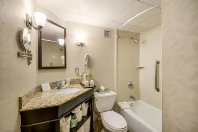 a bathroom with a toilet and a sink and a tub at Exton Hotel and Conference Center in Exton