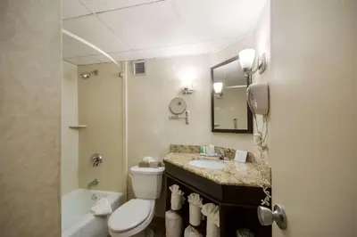 a bathroom with a toilet and a sink and a mirror at Exton Hotel and Conference Center in Exton