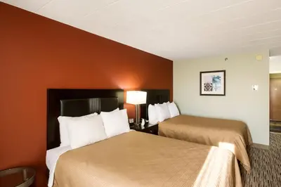 two beds in a hotel room with orange walls at Exton Hotel and Conference Center in Exton
