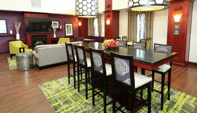 a dining room and living room with a table and chairs at Hampton Inn and Suites of Lamar in Mill Hall