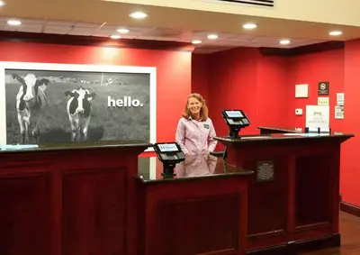 a woman standing behind a podium in a room with two cows at Hampton Inn and Suites of Lamar in Mill Hall