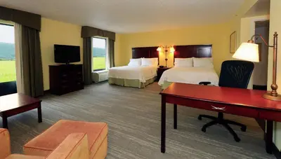 a hotel room with two beds and a desk at Hampton Inn and Suites of Lamar in Mill Hall