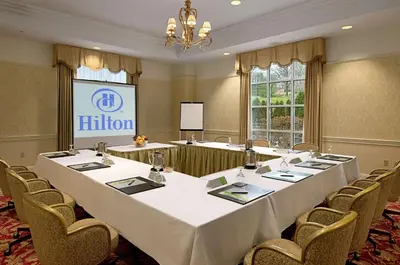 a conference room with tables and chairs and a screen at Hilton Pearl River in Pearl River