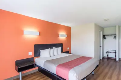 a large bed in a room with an orange wall at Motel 6 New Brunswick in New Brunswick