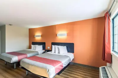 two beds in a room with orange walls at Motel 6 New Brunswick in New Brunswick
