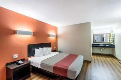 a hotel room with a large bed with orange walls at Motel 6 New Brunswick in New Brunswick