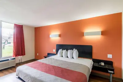 a bedroom with a large bed with an orange wall at Motel 6 New Brunswick in New Brunswick