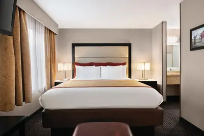 a bedroom with a large bed with white sheets and red pillows at Lancaster Suites in Lancaster