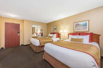 a hotel room with two beds and a bathroom at Lancaster Suites in Lancaster