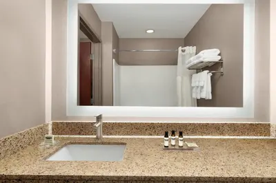 a bathroom with a sink in front of a mirror at Lancaster Suites in Lancaster