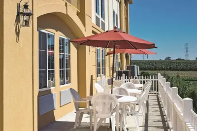 a row of tables and chairs with a red umbrella at La Quinta by Wyndham Lancaster in Lancaster