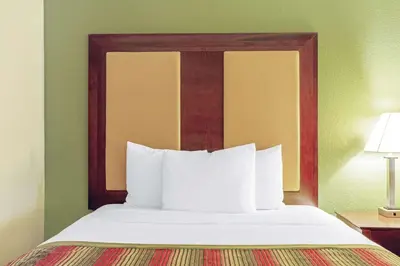 a bed with a wooden headboard in a hotel room at La Quinta by Wyndham Lancaster in Lancaster