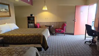 a hotel room with two beds and a table and chairs at Classic Inn Lancaster in Lancaster