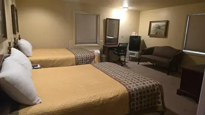 a hotel room with two beds and a chair at Classic Inn Lancaster in Lancaster