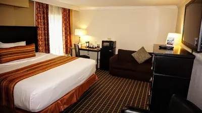 a hotel room with a bed and a chair at The Wilshire Grand Hotel in West Orange