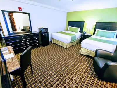 a hotel room with two beds and a couch at The Wilshire Grand Hotel in West Orange