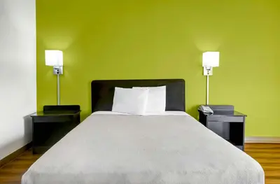 a bed in a room with green walls and two lamps at Motel 6-Lawrenceville, NJ in Lawrenceville