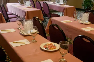 a row of tables with pink table cloths and a plate of food at Meadowlands Plaza Hotel in Secaucus