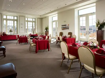 a dining room with red tables and chairs and windows at Grand Eastonian Hotel & Suites in Easton