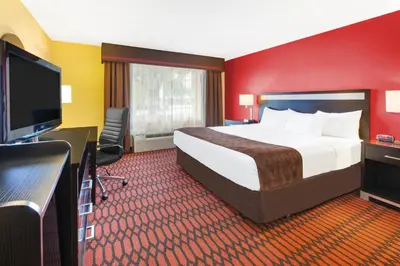 a hotel room with a bed and a flat screen tv at Baymont by Wyndham Harrisburg in Harrisburg