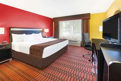 a hotel room with a bed and a flat screen tv at Baymont by Wyndham Harrisburg in Harrisburg