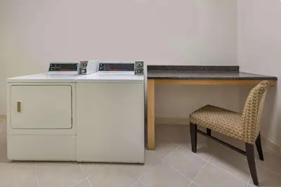 a washing machine and a chair next to a counter at Baymont by Wyndham Harrisburg in Harrisburg