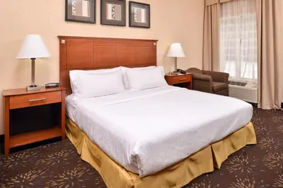a hotel room with a large bed and a chair at Holiday Inn Express Hotel & Suites West Chester by IHG in West Chester