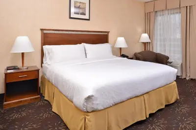 a hotel room with a large bed and a chair at Holiday Inn Express Hotel & Suites West Chester by IHG in West Chester